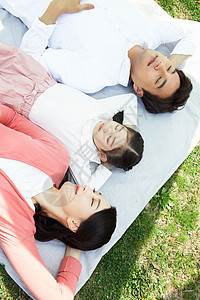 躺在野餐垫上休息的三口之家图片