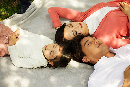 躺在野餐垫上休息的一家人图片