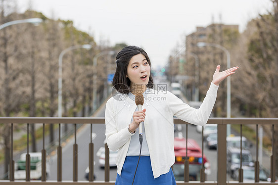 桥上拿着话筒介绍的女记者图片