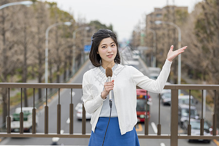 户外拿着麦克风播报新闻的女记者背景图片