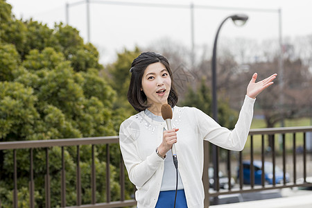 户外拿着麦克风播报新闻的女记者图片