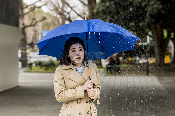 下雨天撑着雨伞播报的年轻女性图片