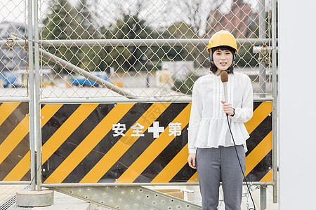 站在建筑工地门口播报新闻的女记者图片