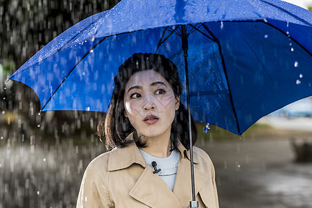 撑着蓝色雨伞的年轻女性图片