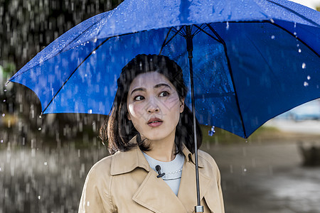 撑着蓝色雨伞的年轻女性背景图片