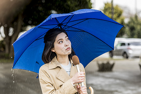 下雨的街道播报新闻的年轻女记者图片素材