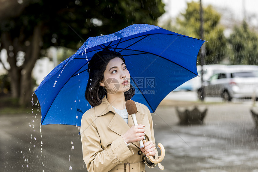 下雨的街道播报新闻的年轻女记者图片