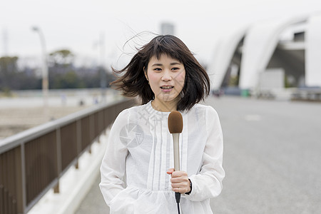 室外台风天播报新闻的年轻女记者背景图片