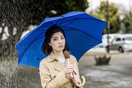 户外下雨的街道播报新闻的年轻女记者图片