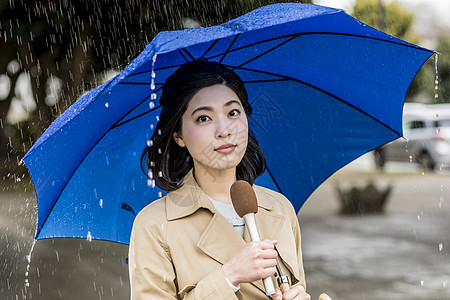 户外下雨的街道播报新闻的年轻女记者图片