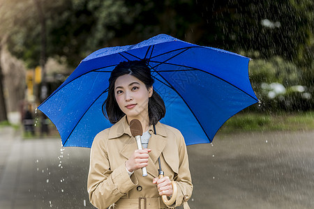 撑着雨伞报道了下雨的街道的女记者背景图片