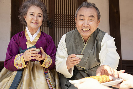穿着传统服装户外喝茶的老年夫妇图片
