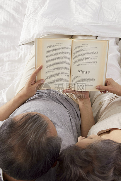 卧室里躺在床上看书的夫妇图片
