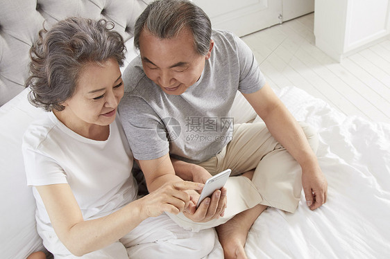 卧室里看着手机的老年夫妇图片