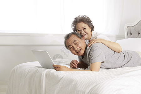 居家床上看笔记本的老年夫妇图片