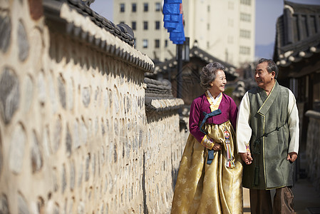 穿着传统服装村子里手牵手散步的老年夫妇图片