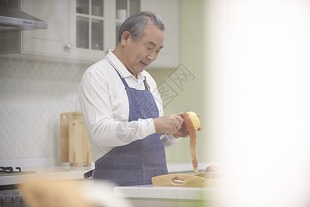厨房里削苹果的老年男性图片