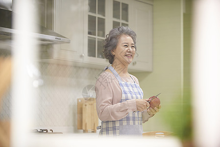 厨房里削苹果的老年女性高清图片