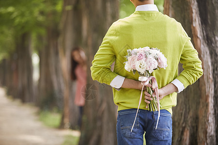 背后拿着一束花的男性图片素材