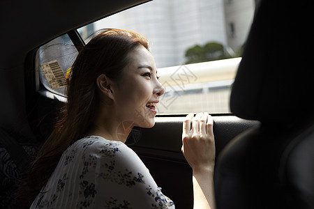 坐在车后座吹风的年轻女子图片