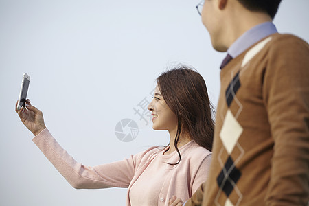 拿着手机拍照的年轻女子图片