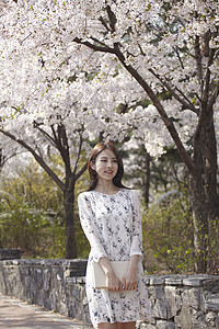 春日站在樱花树下微笑的女大学生图片
