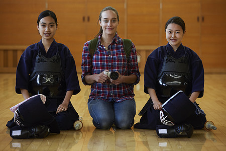 坐在剑道少女中间拿着相机的留学少女图片