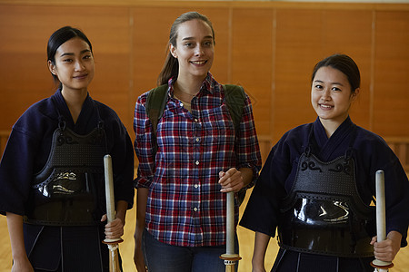 拿着木剑站在剑道少女中间的女孩图片