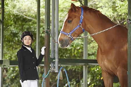 骑马俱乐部的穿着马术服装的年轻女性图片