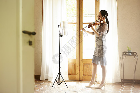 站在窗口拉小提琴的气质女性图片