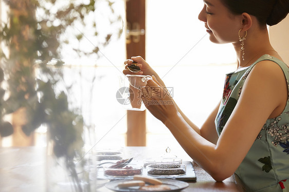 优雅的泡茶的年轻女性图片