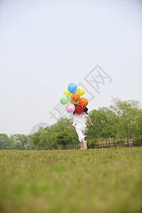 草坪上拿着气球奔跑的小孩图片