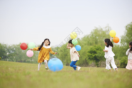 北湖公园草坪上拿着气球奔跑的孩子们背景