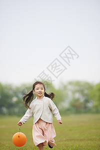 草坪上拿着气球奔跑的小女孩图片