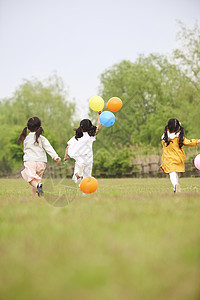 草坪上拿着气球奔跑玩耍的孩子们图片