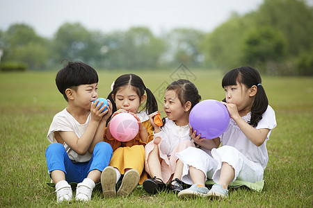 坐在草坪上吹气球的孩子们图片
