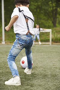 公园里踢足球的小男孩背影图片