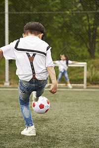公园里踢足球的小男孩背影图片