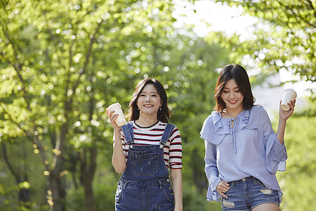 和朋友一起聊天喝咖啡散步的年轻女子图片