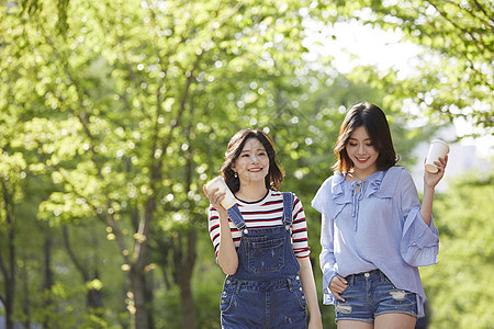 和朋友一起聊天喝咖啡散步的年轻女子图片