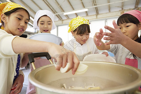 将食材放入大锅烹饪的姑娘们图片