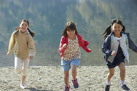 假期户外活动小学生在河边奔跑图片