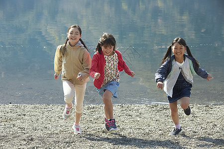 假期户外活动小学生在河边奔跑图片