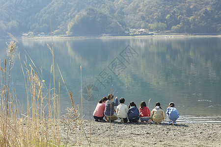 假期户外活动小学生在河边蹲下休息图片