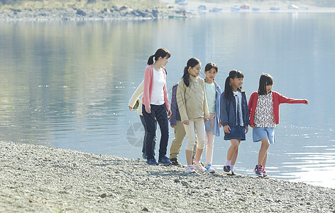 假期户外活动小学生和老师在河边散步图片