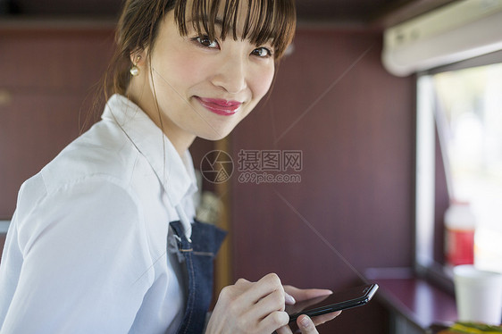 餐车里拿着手机微笑的年轻女性图片
