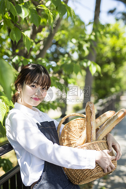 抱着一筐新鲜面包的年轻女性图片