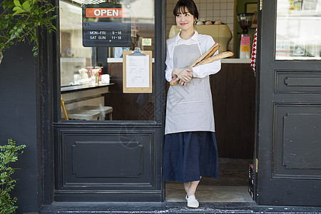 咖啡馆门口年轻女性抱着新鲜出炉的法式面包图片