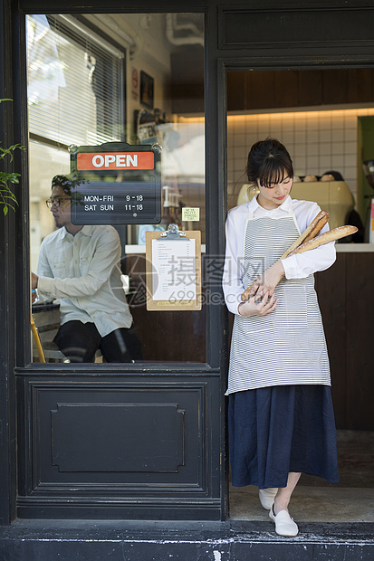 咖啡馆年轻女性抱着新鲜出炉的法式面包图片