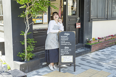 站在咖啡馆广告牌旁边的年轻女性图片